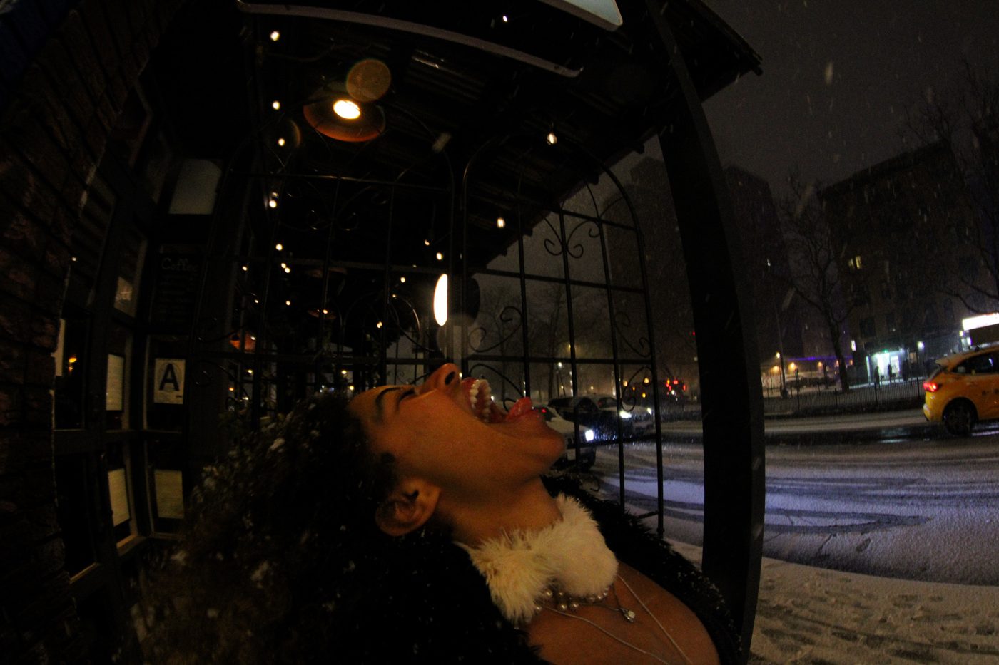 Hailey laughing up at the falling snow at night