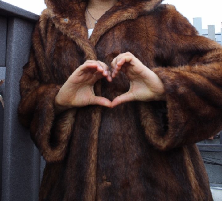 Hands making a heart against a fur coat